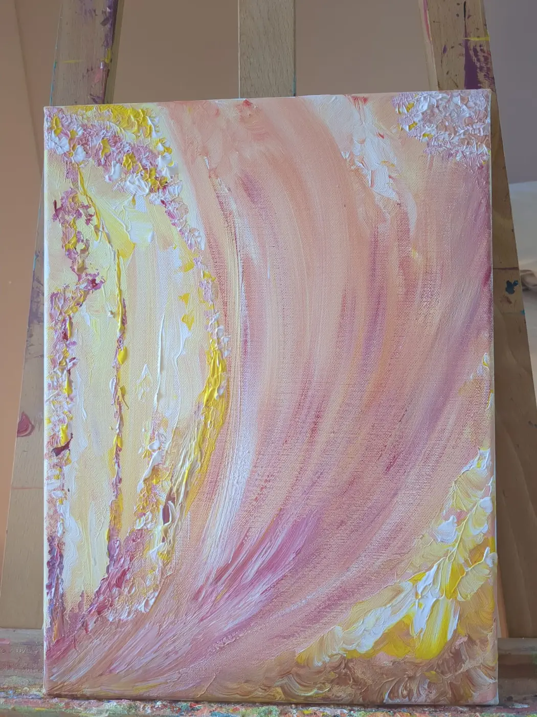 Een groot schilderij van Edith in roze, zacht geel en lila op een ezel