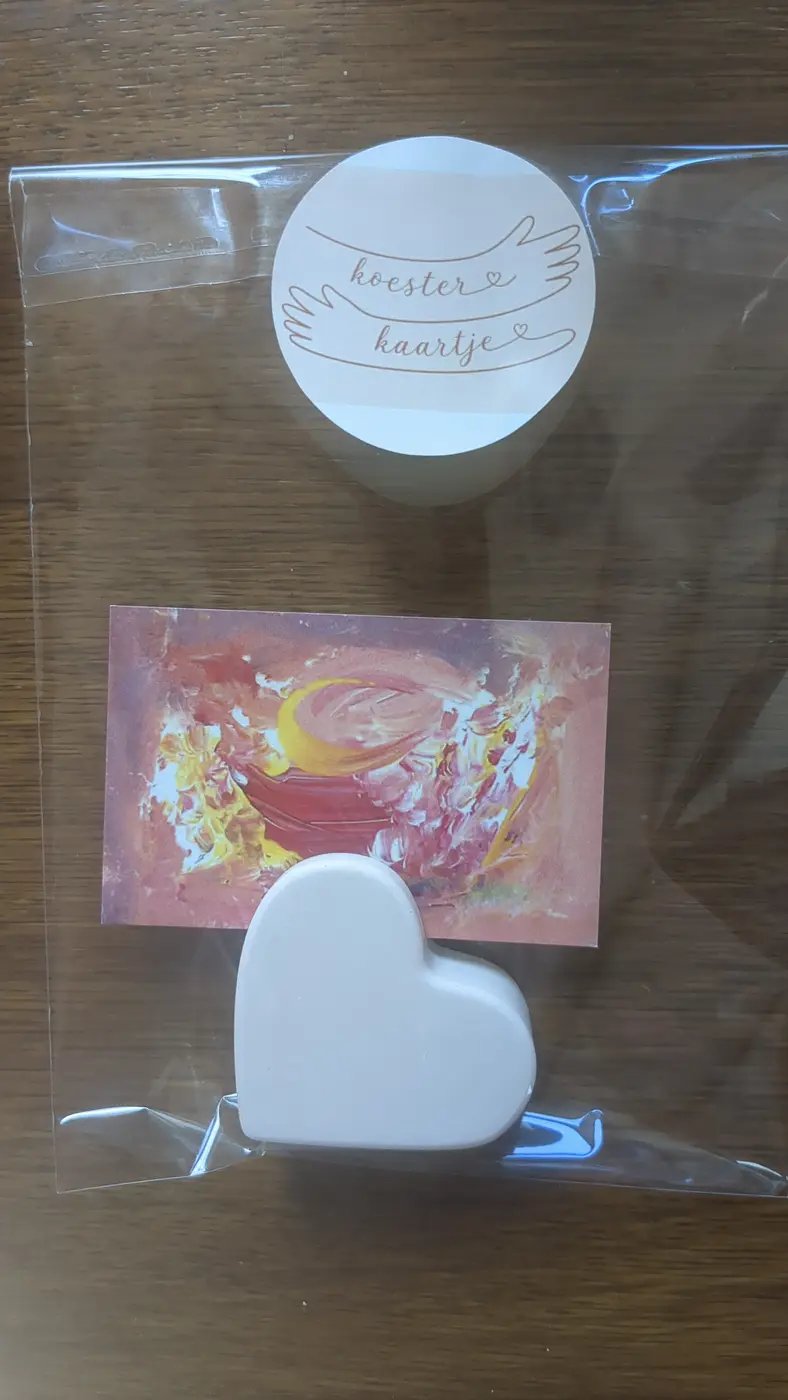 Een koesterkaartje met een hartvormige houder, verpakt in een zakje met de ronde koesterkaartje-sticker